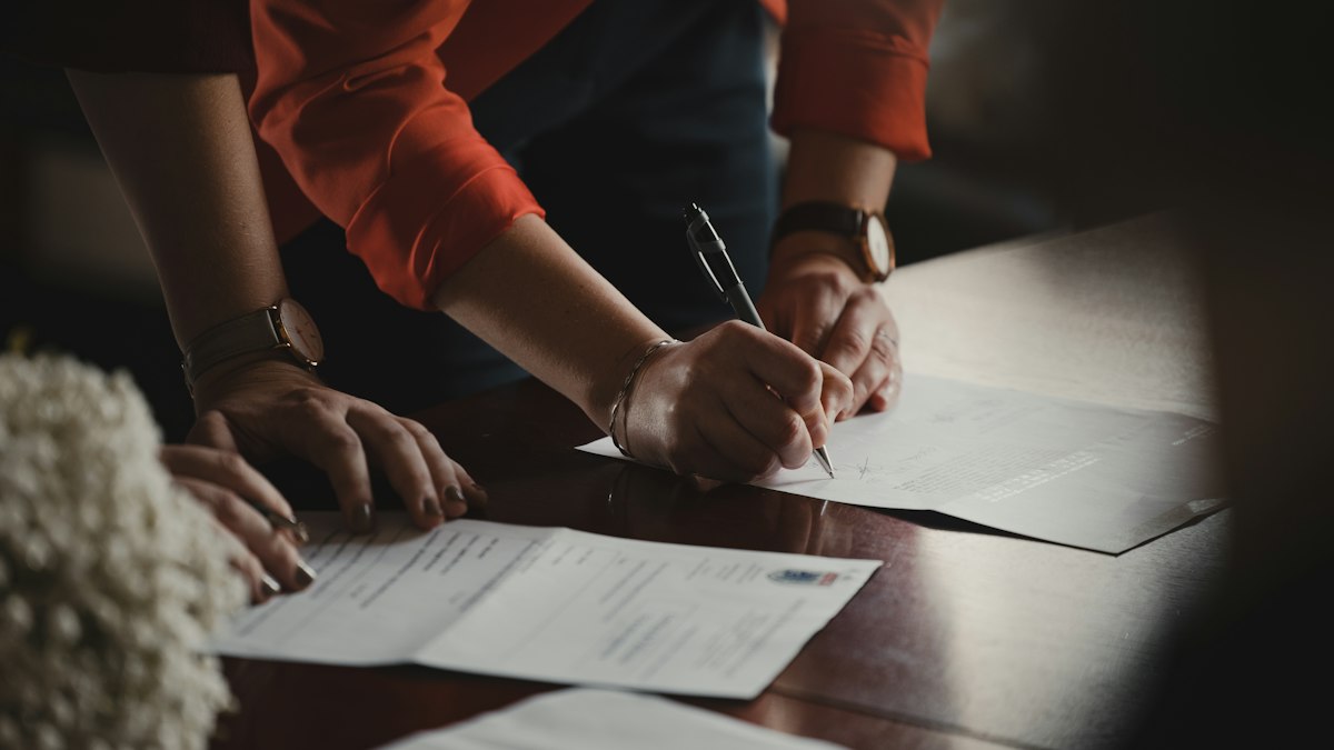 Two people signing a legal contract at a desk