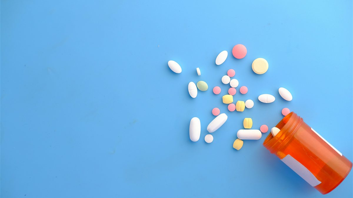 Colorful prescription pills spilling from an orange pill bottle