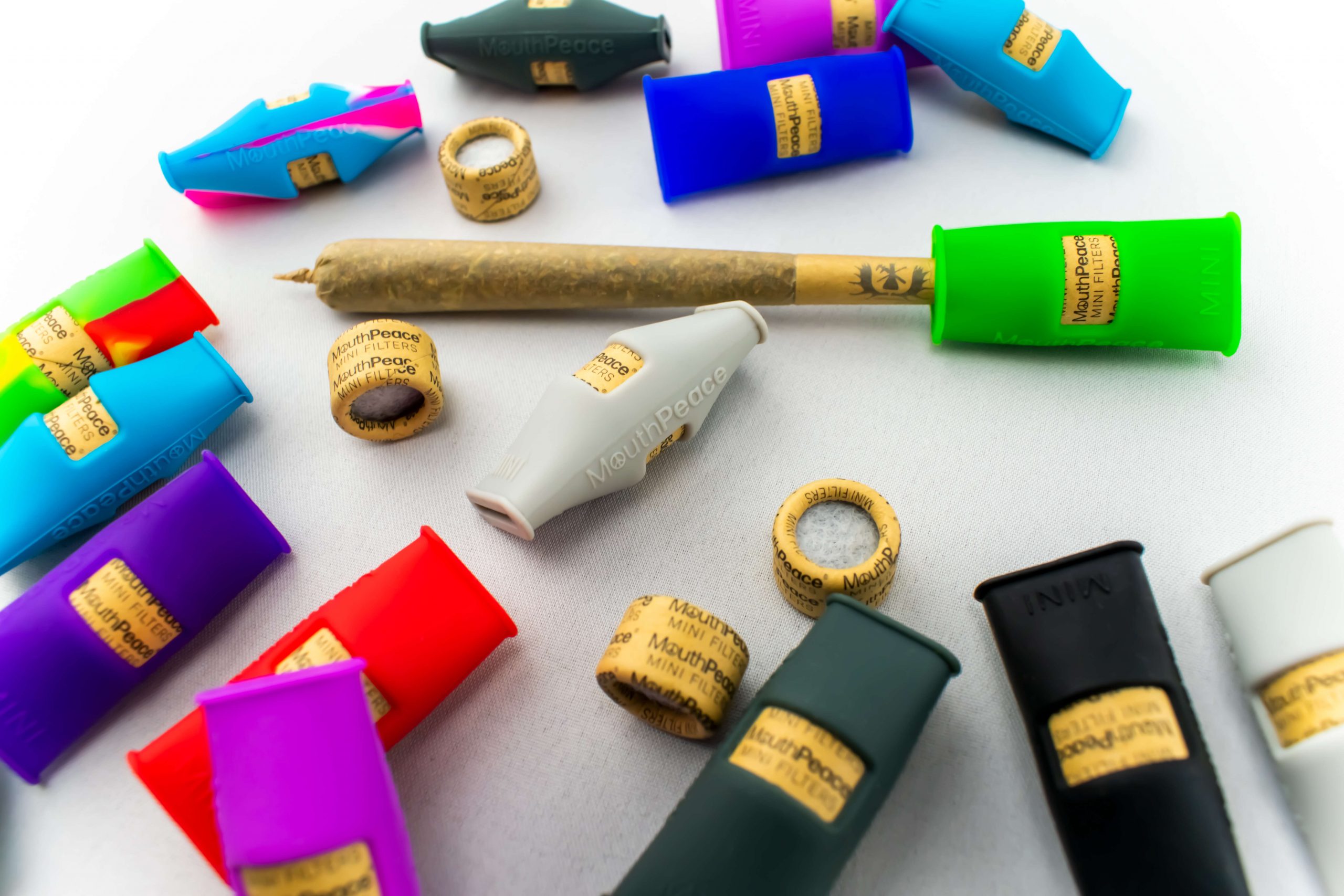 Colorful Moose Labs MouthPeace Mini mouthpieces and filters arranged around a pre-roll