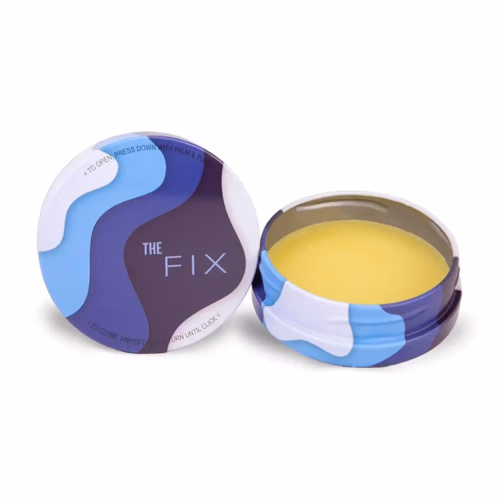 An open tin of yellow The Fix cooling balm beside its blue and purple lid